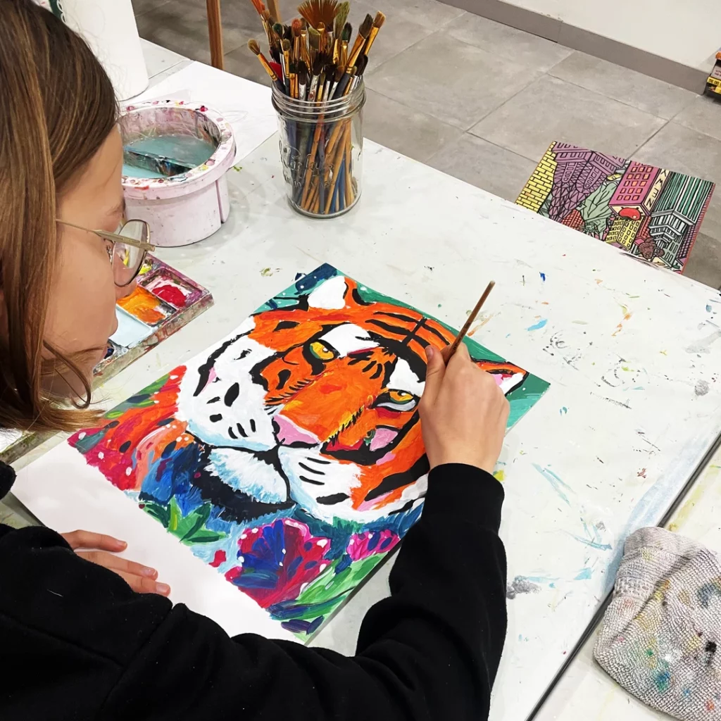 jeune fille peignant un tigre lors d'un cours d'arts plastiques à l'Atelier Amarillo